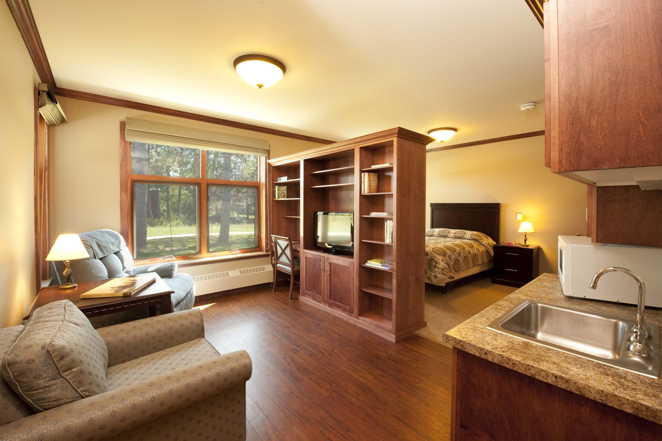 The resident rooms are bright open spaces with a custom divider wall that provides storage, a desk, and space for a tv.